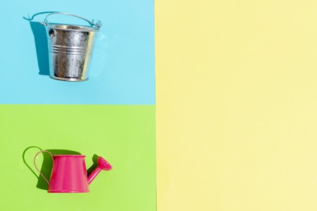 Watering can and bucket on a colorful background. Hello summer.