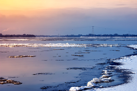 Ice on the river during the ice drift lit by the setting sun in the spring