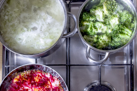 Cooking fresh vegetables in pots and pans. Top view.