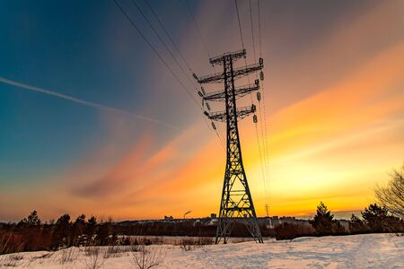 High voltage electricity pylons and transmission power lines on the blue sky background at sunsetの写真素材
