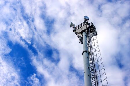 Cell tower transmitting signals of mobile phone and Internet against the blue sky. Bottom view