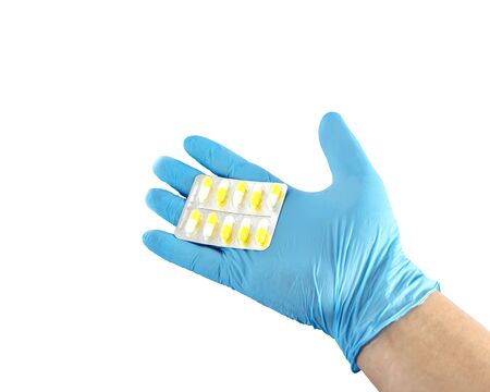 Male hand in a medical glove holds a handful of yellow pills. Isolated on white photo.の写真素材