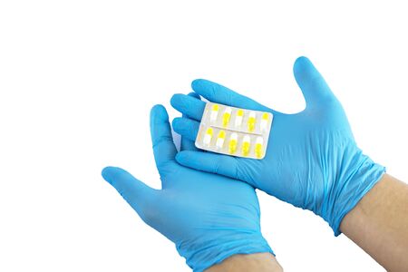 Male hand in a medical glove holds a handful of yellow pills. Isolated on white photo.の写真素材