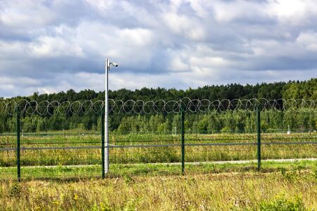 Fence, barbed wire and video camera. Obstruction and surveillance observation.の写真素材