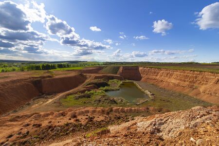 Abandoned sand pit with a lake on a background of blue sky with cloudsの写真素材