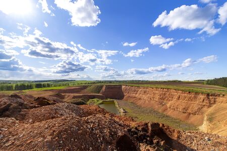 Abandoned sand pit with a lake on a background of blue sky with cloudsの写真素材