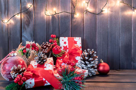 Christmas decoration with pine branches, red ball, and red berries with gifts on wooden background. Flat layの写真素材