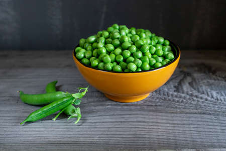 Fresh green peas in cup on wooden background. Rustic table backgroundの写真素材