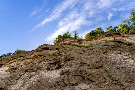 Rock with soil layers against blue skyの写真素材
