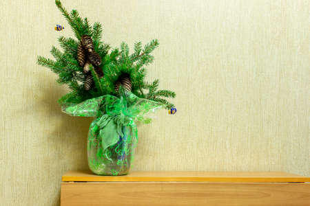 A bunch of fir branches stands on the edge of a wooden table. Christmas compositionの写真素材