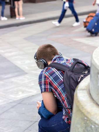 MOSCOW - JULY 14, 2019: Guy with headphones sitting on the streetのeditorial素材