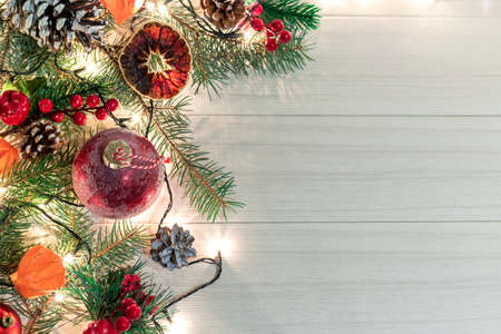 Christmas decoration with spruce branches with a red ball and a garland. Winter holiday light decoration. Top view.の写真素材