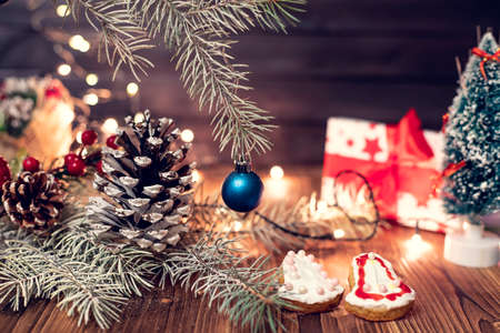 Happy new year and Christmas decor with cedar cone and christmas lights, with spruce branches on wooden background. Selective focus. Soft focus.の写真素材