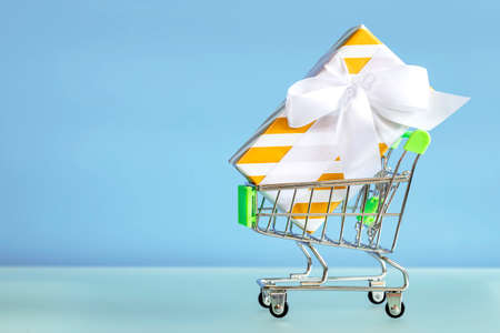 Giftbox and shopping cart on blue background. New Year gifts. New year discountsの写真素材