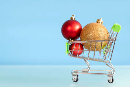 Christmas balls and shopping cart on blue background. New Year gifts. New year discountsの写真素材