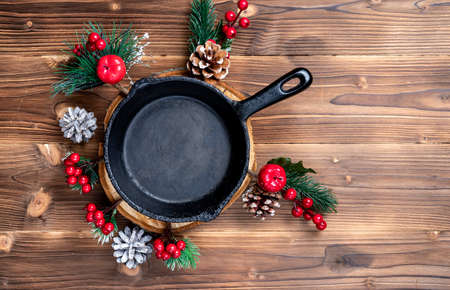 Vintage cast iron skillet on rustic wood background. Food background with copyspace. New Year and Christmas menu in a cafe and restaurantの写真素材