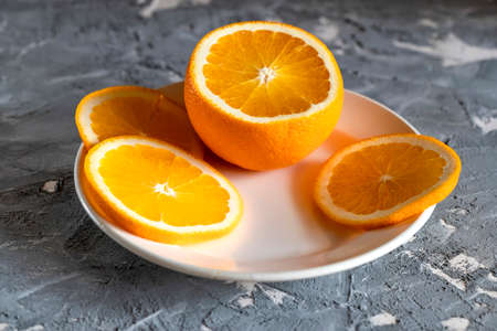 Sliced orange on a white plate on dark wooden tableの写真素材