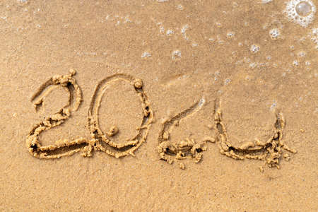 2020 text painted on the sand. Water washed away the text on the beach. The 2021 year is comingの写真素材