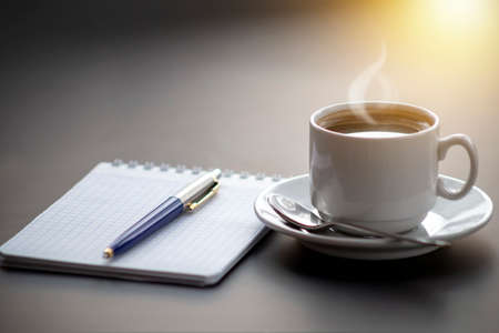 A cup of coffee with steam on the table. Planning and starting the day.の写真素材
