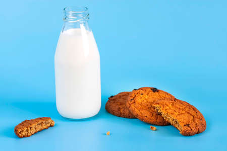 Bottle with milk and oatmeal cookies on a blue backgroundの写真素材