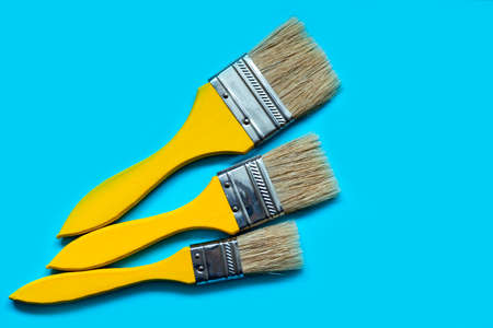Yellow paint brushes on a blue background. Flat lay styleの写真素材