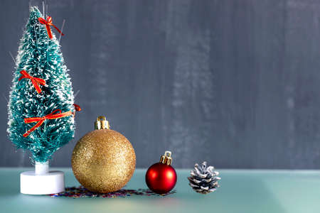 A small handmade Christmas tree stands next to Christmas balls and a pine coneの写真素材