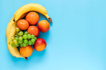 Oranges, bananas and grapes on blue background. Healthy and fresh fruits.の写真素材