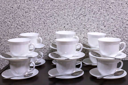 Many empty white cups with spoons stand on the tableの写真素材