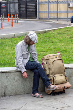 MOSCOW - JULY 14, 2019: A tired man traveler sits and smokes at the train station.のeditorial素材