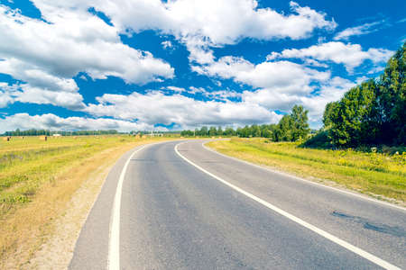Asphalt road leading into the distance around the bendの写真素材