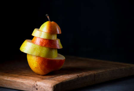 Pear cut into pieces on a dark background. Concept of the morning breakfast. Close-up with copy space.の写真素材