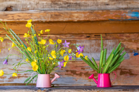 Fresh herbs and wildflowers in small watering cans on the old wooden background. Summer fresh conceptの写真素材