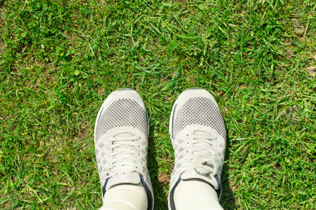 Selfie of shoes standing on the grass. View from above of man feet in light sneakers on green lawn. Empty place for text, copy spaceの写真素材