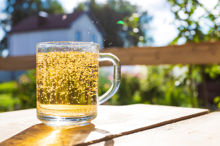 A glass with lemonade stands on a wooden table in the garden on sunny dayの写真素材