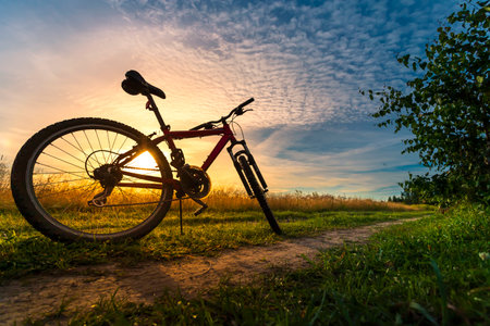 Bicycle silhouette at the sunset dirt road in the countryside. Idea and concept of physical activity and healthy lifestyleの写真素材
