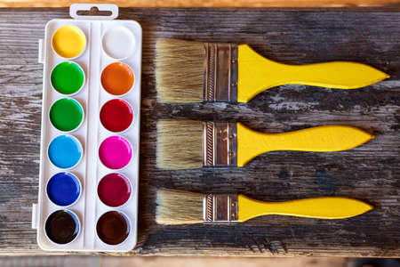 Yellow brushes and watercolor paints on an old wooden table. Top viewの写真素材