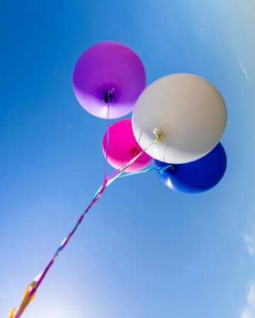 Multicolored inflatable balloons filled with helium against the blue skyの写真素材