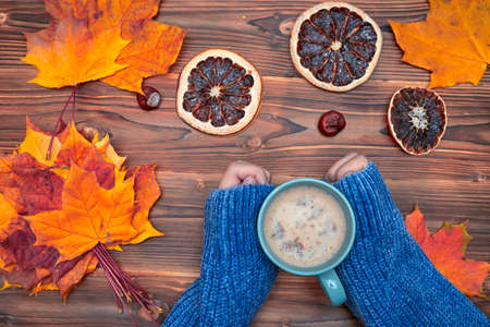 Autumn flat lay. Female hands with cup of coffee, over colorful maple leaves background. Top view. Season conceptの写真素材