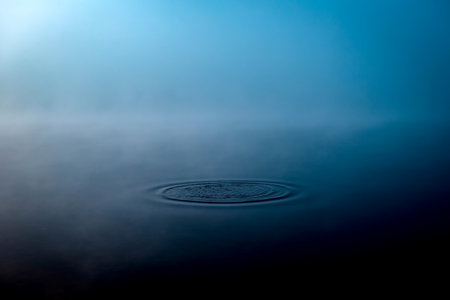 Thick morning fog on the lake or river. Circles on the water. Relaxation and meditation banner.の写真素材