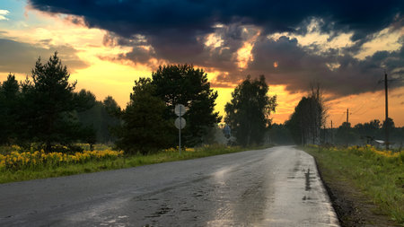 Asphalt road among the fields at sunset. Summer sunset with road.の写真素材
