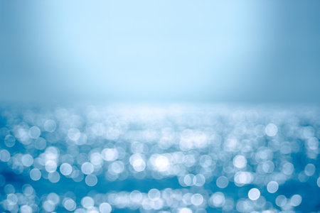 Delicate blue texture bokeh sea. Summer background. Blurry blue bokeh glare on the water on a sunny day. Concept travel.の写真素材