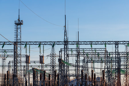 High voltage electrical insulators in power transmission substation against blue sky background; wires, cables, insulators at electrical power station, power grid infrastructureの写真素材