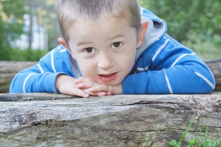 Portrait of beautiful boy resting on a log の写真素材
