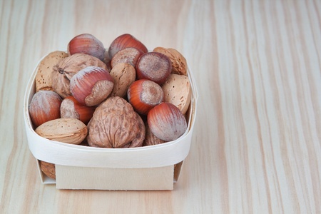 Basket with wood, walnuts and almonds  On a wooden texture 