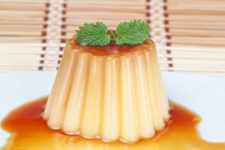 Delicious sweet pudding with caramel and mint leaves on a decorative napkin.の写真素材