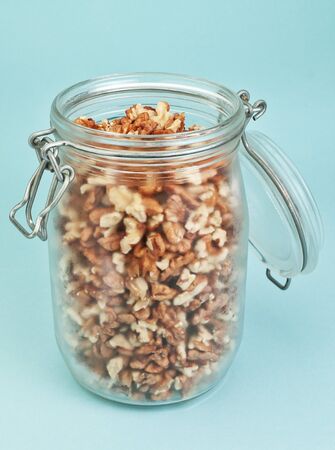 Glass jar with walnuts  On a blue background の写真素材