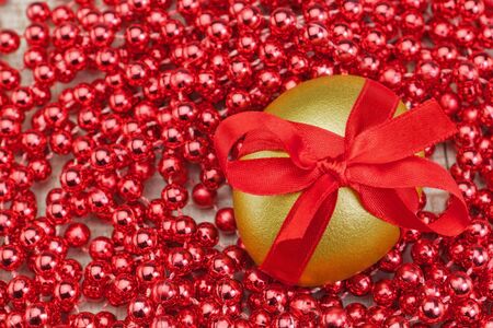 Golden egg in a bow on a background of beads, jewelry,の写真素材