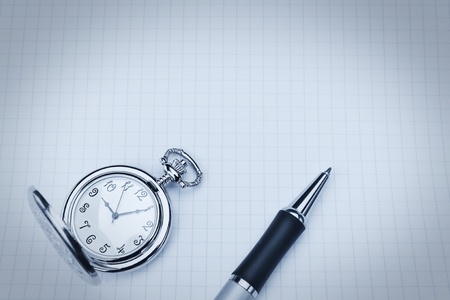 Pocket watch and ballpoint pen on notebook in cool blue tones.の写真素材