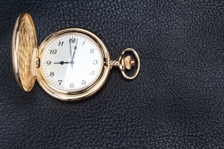 Antique gold pocket watch on a textured black leather  Close-up の写真素材