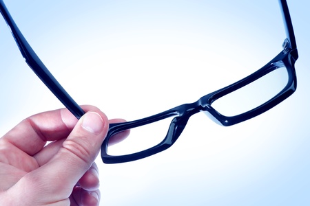 Glasses in the hand of a man in blue tones.